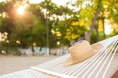 Photo of Comfortable hammock with straw hat and sunglasses at seaside