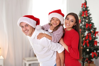 Happy parents and child having fun near Christmas tree at home