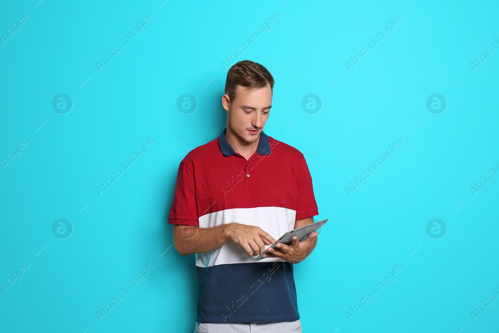 Photo of Young man with tablet on color background