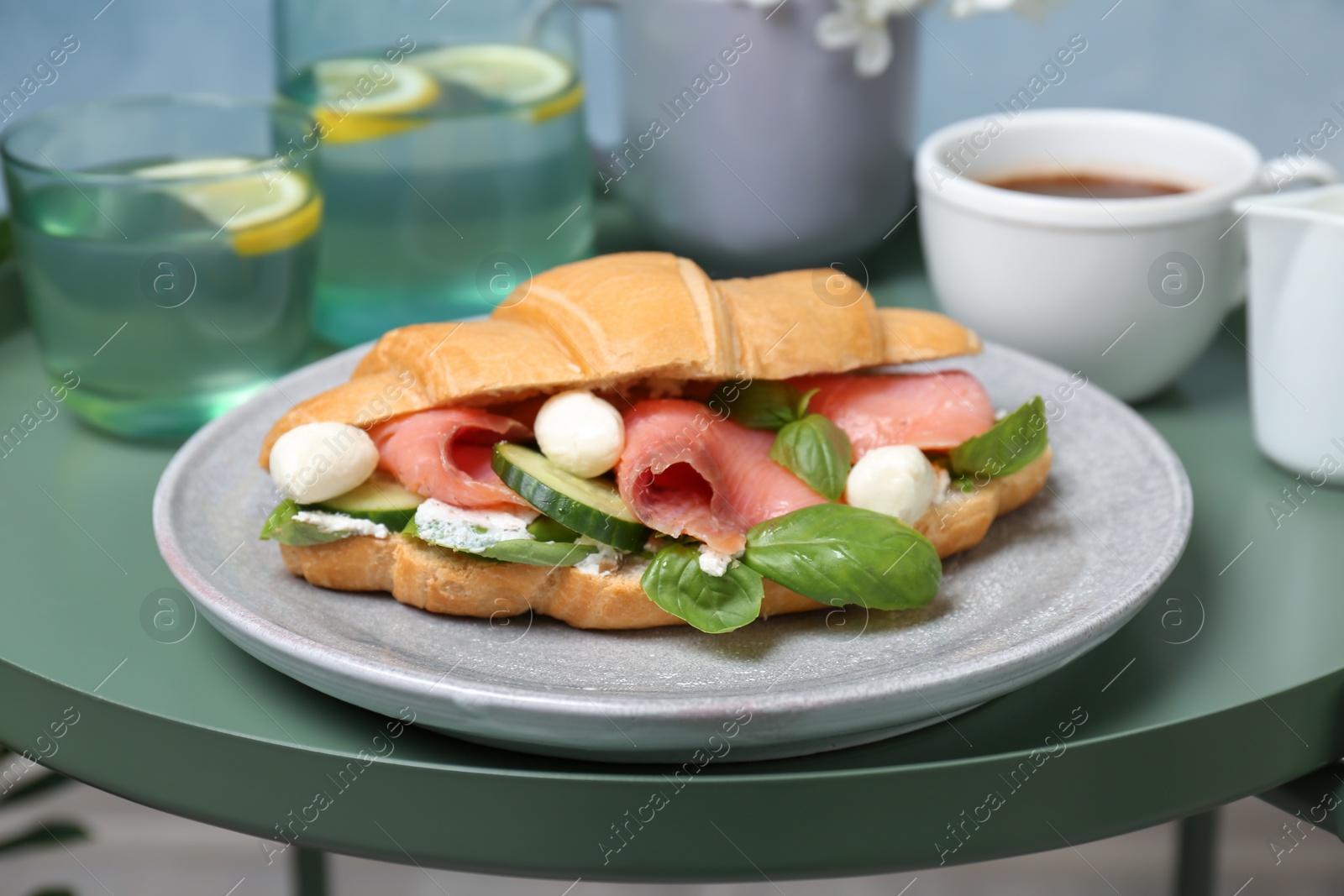 Photo of Plate with tasty croissant sandwich on table