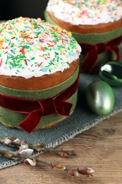 Traditional Easter cakes, painted eggs and willows on wooden table, closeup