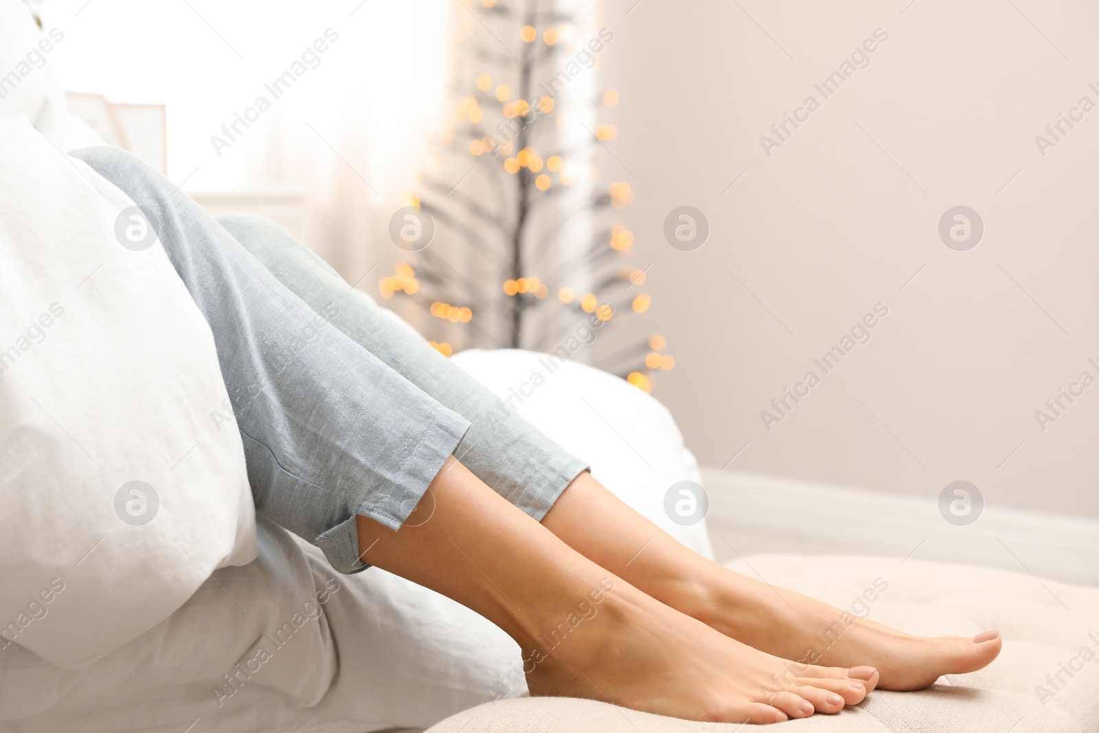 Photo of Woman sitting on bed in decorated room, closeup