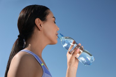 Photo of Beautiful young sportswoman drinking water outdoors. Refreshing drink