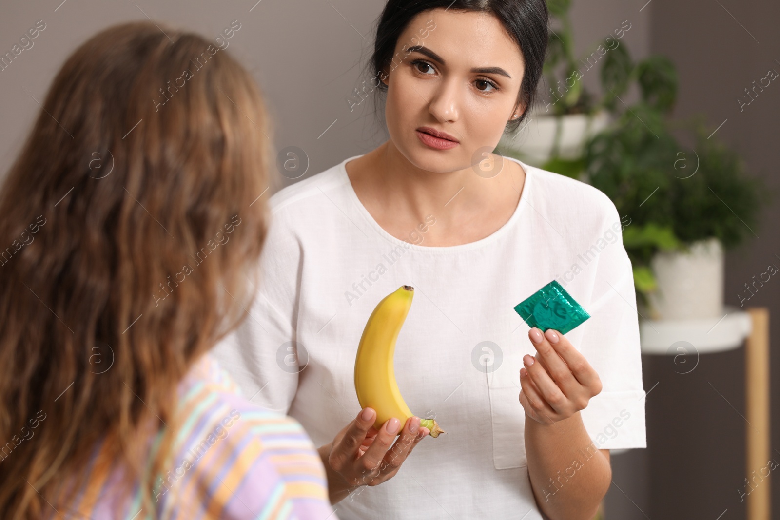 Photo of Mother talking with her teenage daughter about contraception at home. Sex education concept