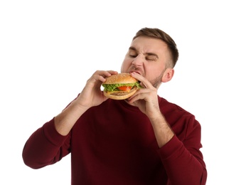 Photo of Young man eating tasty burger on white background