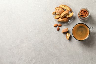 Photo of Slices of tasty cantucci, aromatic coffee and nuts on light grey table, flat lay with space for text. Traditional Italian almond biscuits