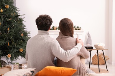 Couple watching movie via video projector at home, back view
