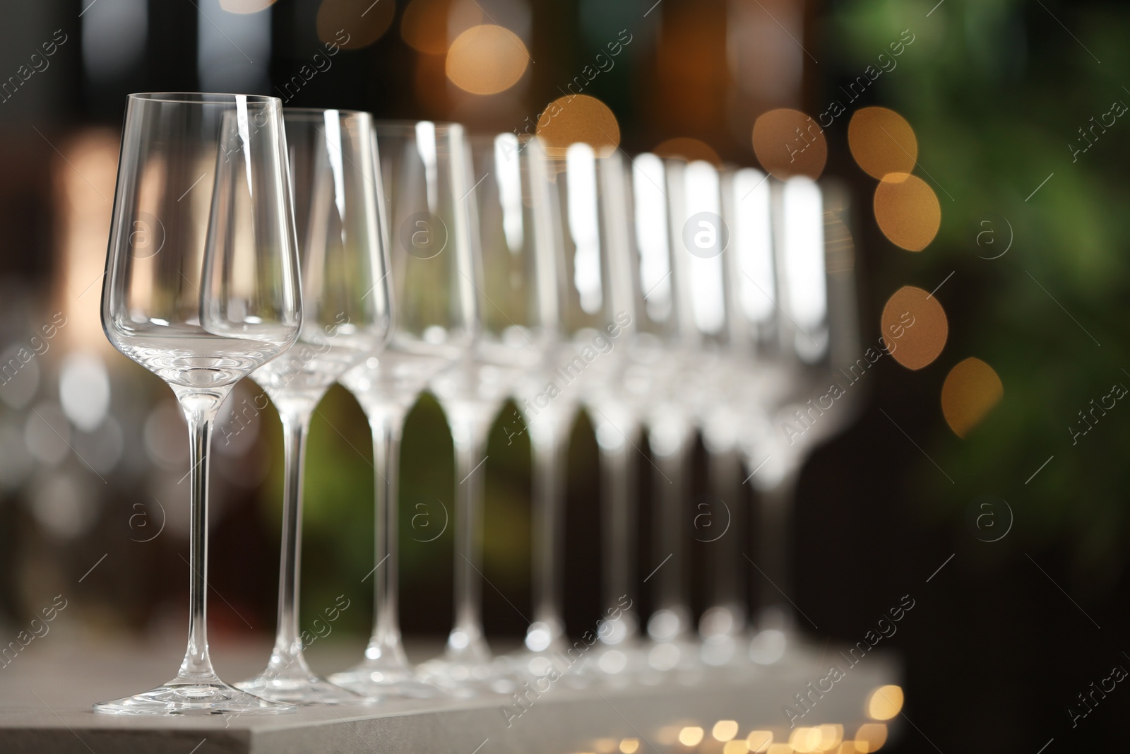 Photo of Set of empty wine glasses on grey table against blurred background