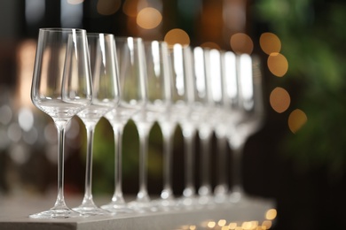 Photo of Set of empty wine glasses on grey table against blurred background