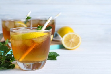 Photo of Delicious iced tea in glass on white wooden table, space for text