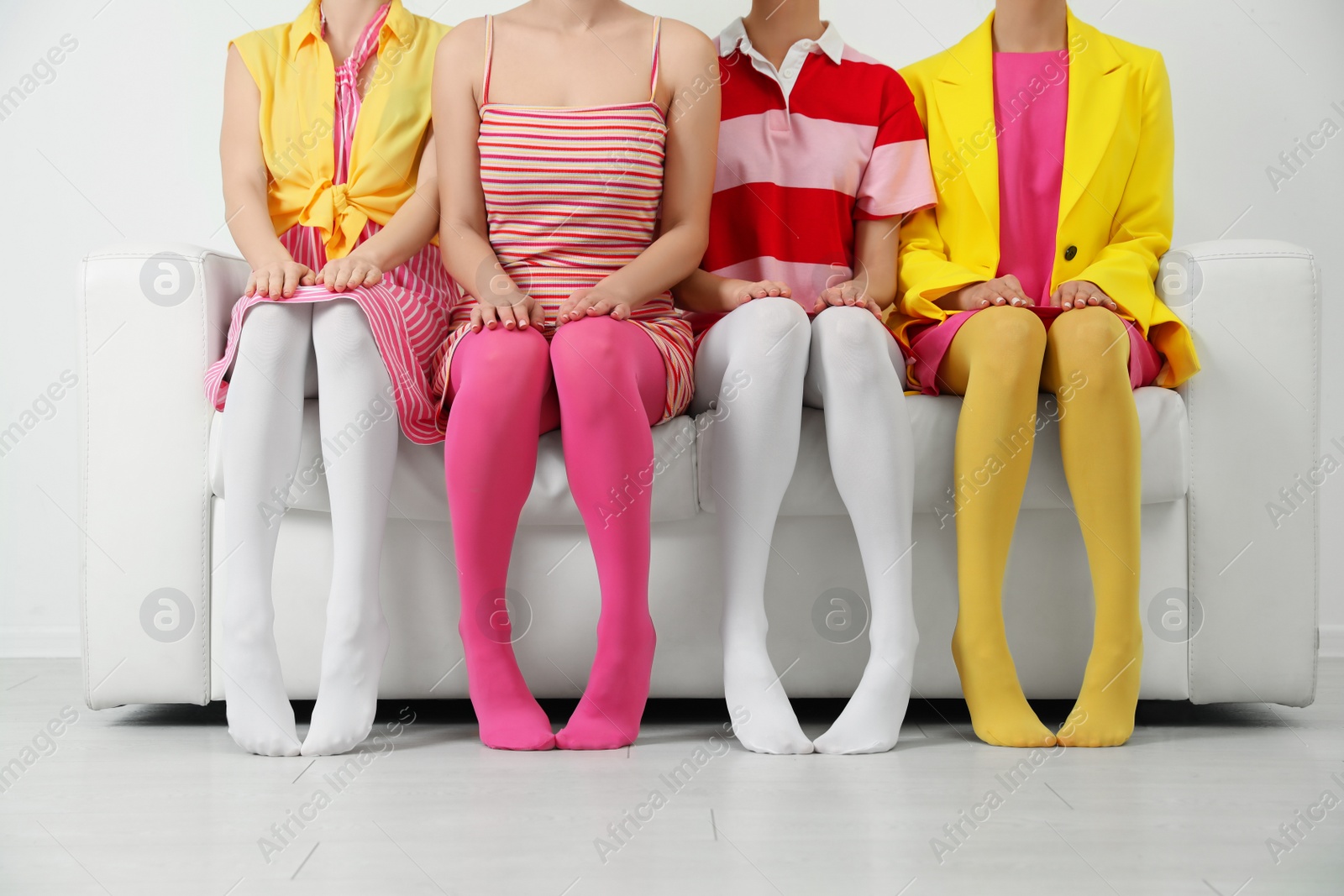 Photo of Women wearing colorful tights sitting on sofa indoors, closeup