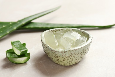 Photo of Bowl with aloe vera gel and fresh leaves on gray table