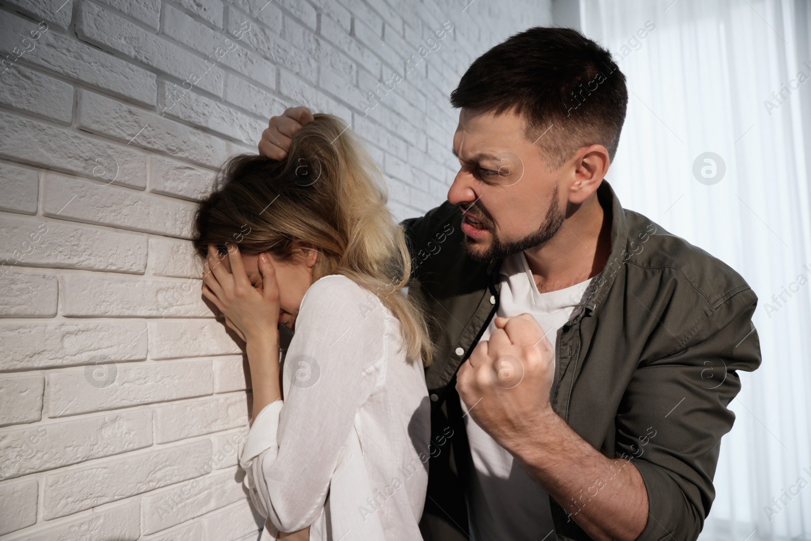 Photo of Man abusing scared woman at home. Domestic violence