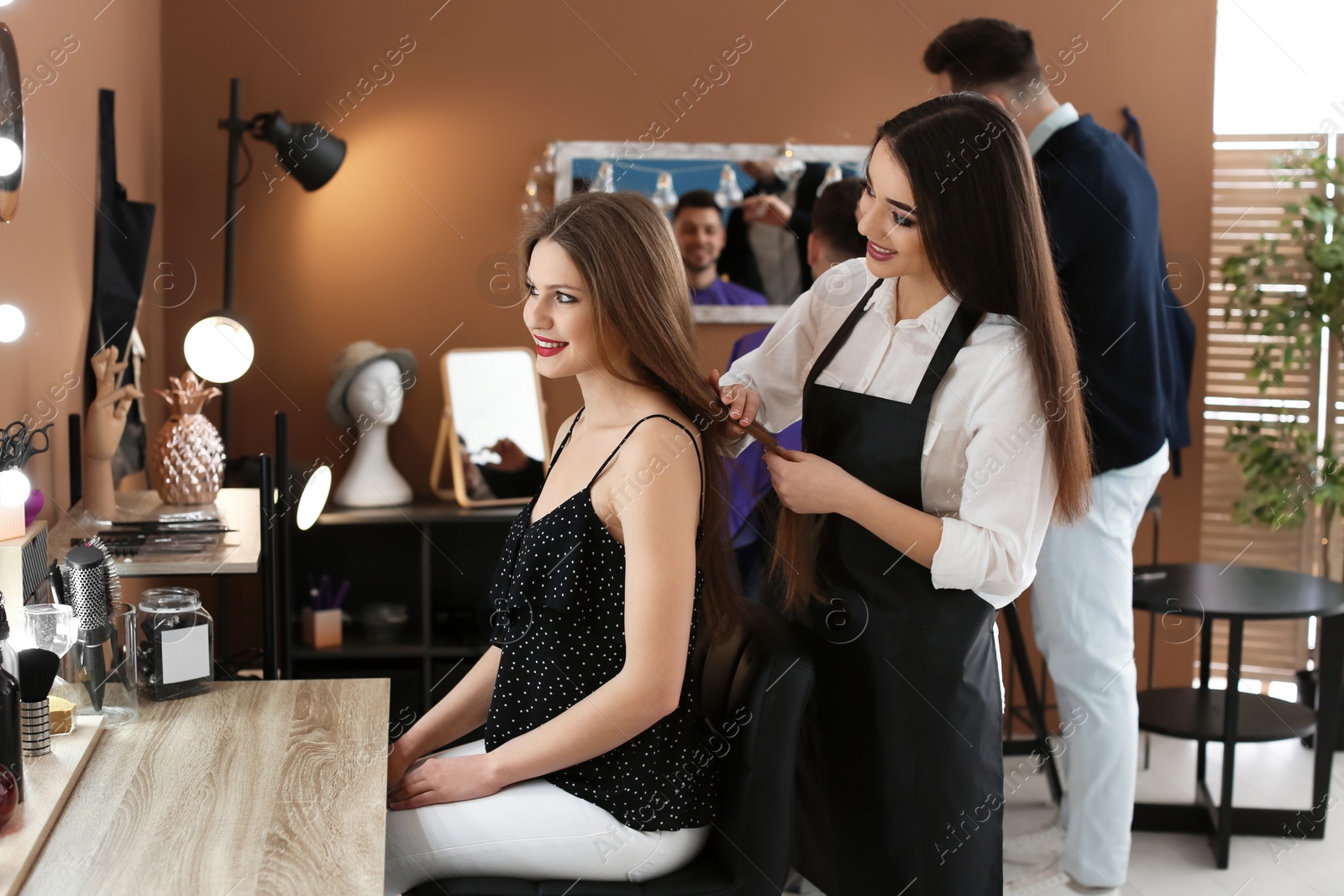 Photo of Professional hairdresser working with client in beauty salon