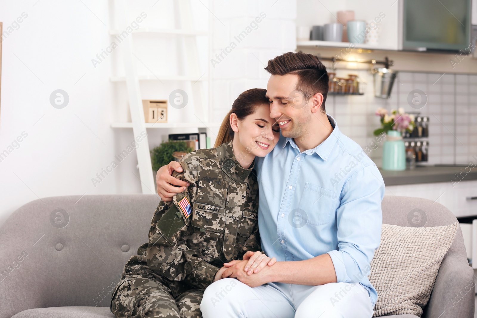 Photo of Woman in military uniform with her husband on sofa at home