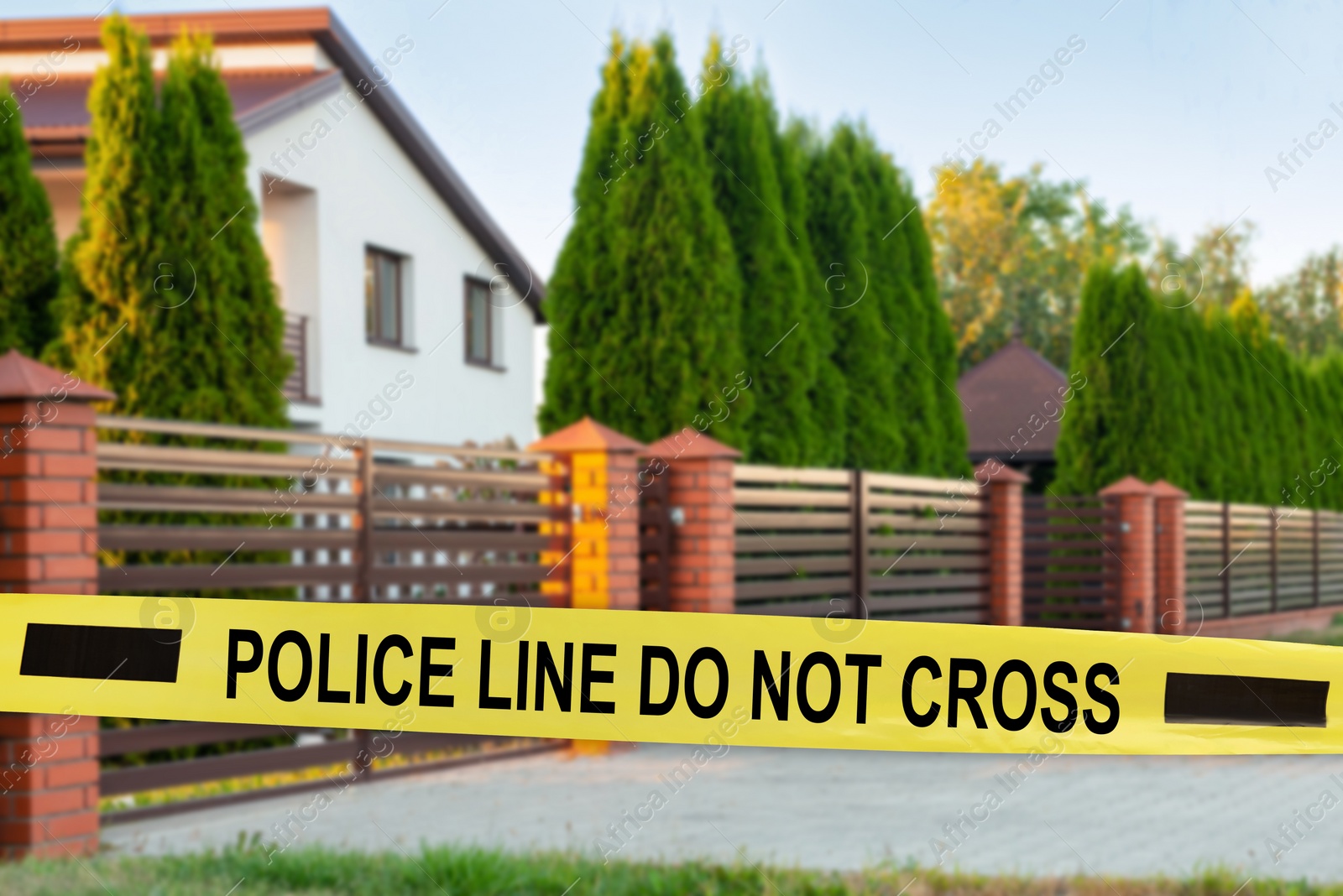 Image of Yellow crime scene tape blocking way to house outdoors