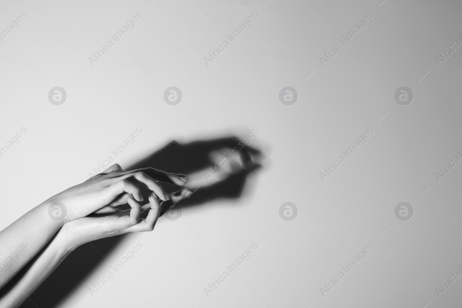 Photo of Shadow puppet. Woman making hand gesture like crocodile on light background, closeup with space for text. Black and white effect