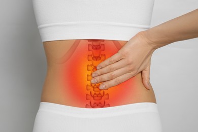 Image of Woman suffering from pain in back on light grey background, closeup