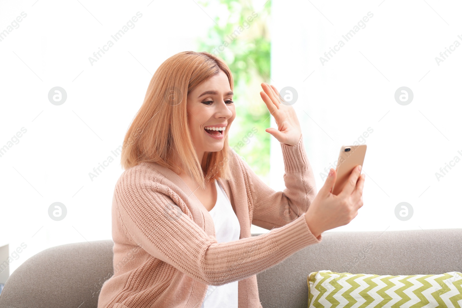 Photo of Woman using mobile phone for video chat in living room