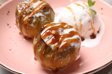 Delicious baked apples with nuts, ice cream and caramel on plate, closeup
