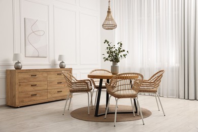 Photo of Dining room interior with comfortable furniture and eucalyptus branches