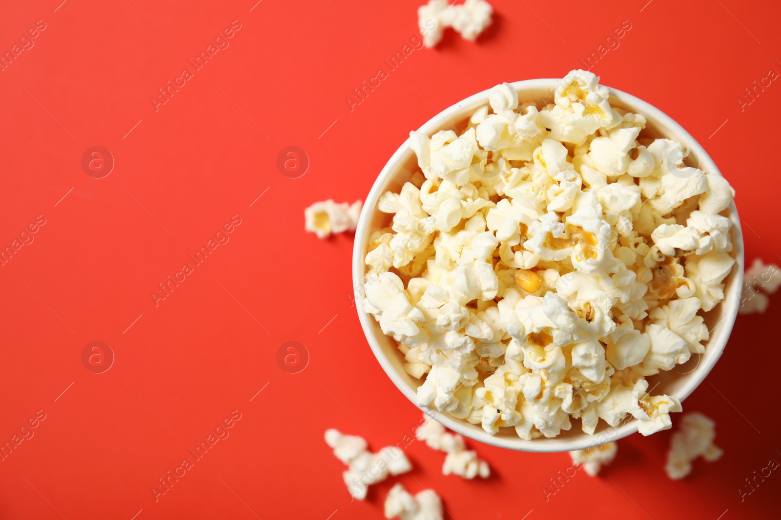 Photo of Fresh tasty popcorn and cup on color background, top view with space for text. Cinema snack