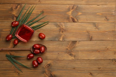 Photo of Palm oil in glass bowl, tropical leaf and fruits on wooden table, flat lay. Space for text