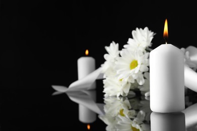 Photo of White chrysanthemum flowers and burning candles on black mirror surface in darkness, closeup with space for text. Funeral symbols