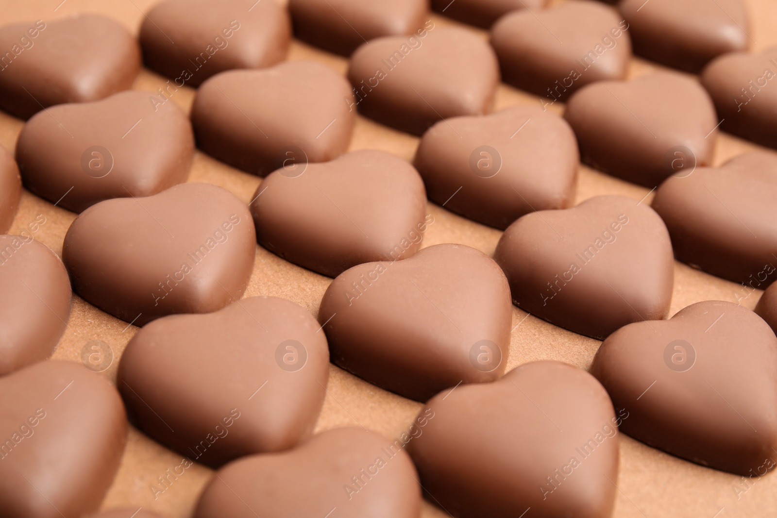 Photo of Tasty heart shaped chocolate candies on brown background, closeup. Valentine's day celebration