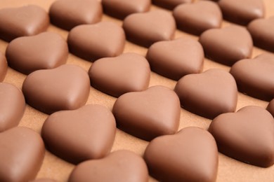 Tasty heart shaped chocolate candies on brown background, closeup. Valentine's day celebration