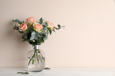 Photo of Vase with bouquet of beautiful roses on white wooden table. Space for text