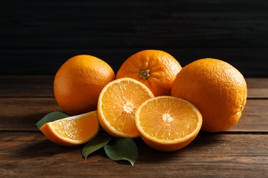 Fresh oranges with leaves on wooden table