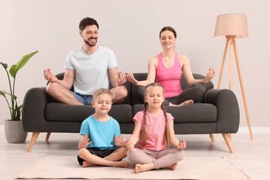 Photo of Happy family meditating together at home. Harmony and zen