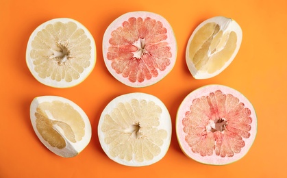 Photo of Fresh cut pomelo fruits on orange background, flat lay