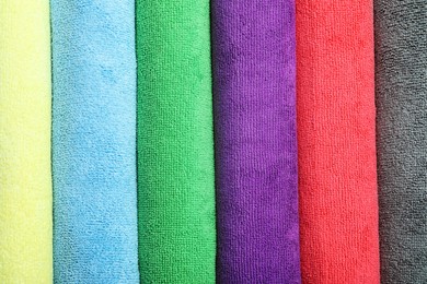 Many colorful microfiber cloths as background, top view