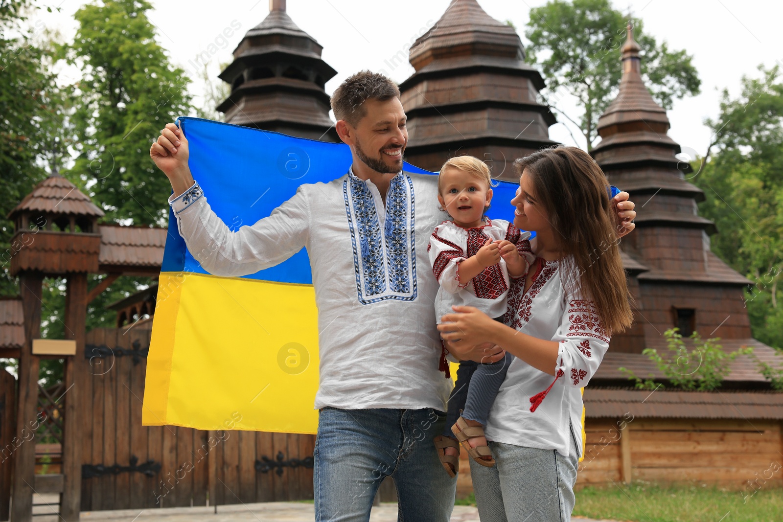Photo of Happy family in national clothes with flag of Ukraine near church