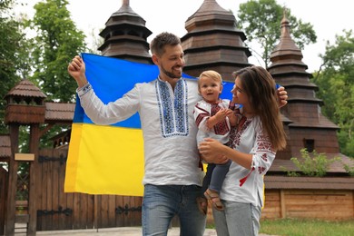 Photo of Happy family in national clothes with flag of Ukraine near church