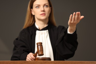 Photo of Judge striking mallet at wooden table in courtroom, selective focus