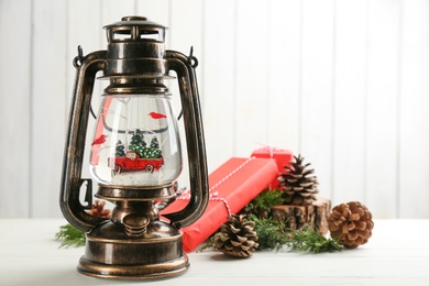Photo of Beautiful Christmas snow globe in vintage lantern and festive decor on white wooden table. Space for text