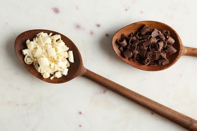 Photo of Spoons with different chocolate curls on light background, top view