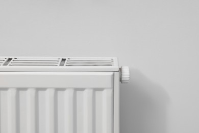 Photo of Modern radiator on white wall, closeup. Space for text