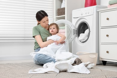 Mother with her daughter washing baby clothes in bathroom