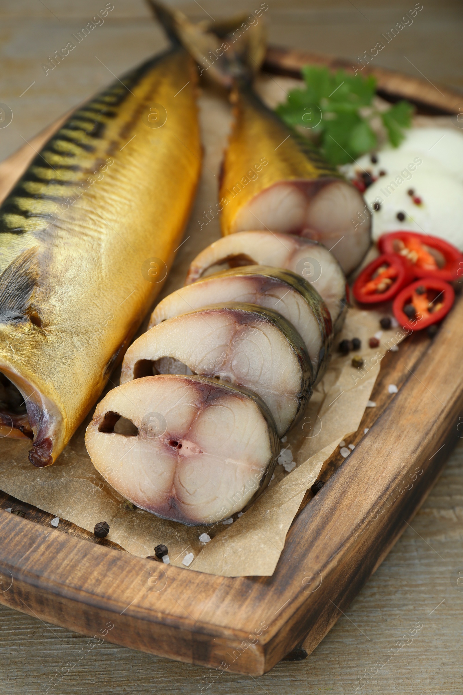 Photo of Delicious smoked mackerels with pepper, onion and spices on wooden table, closeup