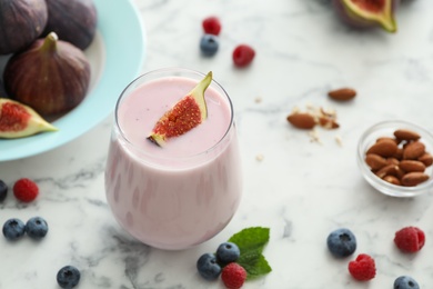 Photo of Delicious fig smoothie in glass on white marble table