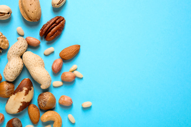 Photo of Different delicious nuts on light blue background, flat lay. Space for text