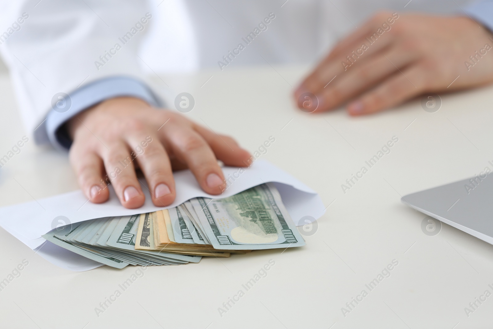 Photo of Doctor with bribe at desk in clinic, closeup. Corrupted medicine