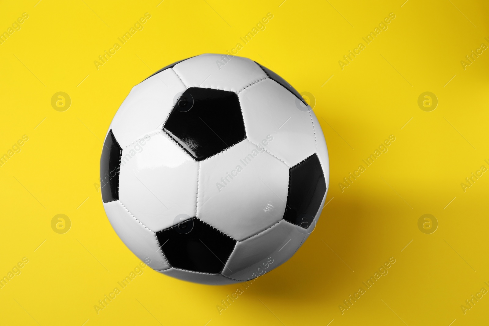 Photo of One soccer ball on yellow background, above view. Sports equipment