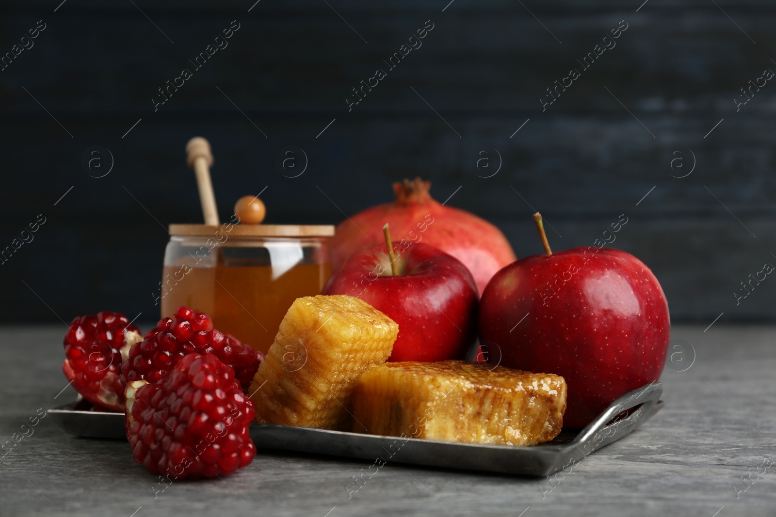 Photo of Honey, apples and pomegranate on grey table. Rosh Hashanah holiday