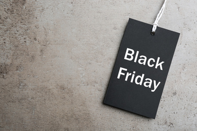 Photo of Top view of blank tag on light grey stone background, space for text. Black Friday concept