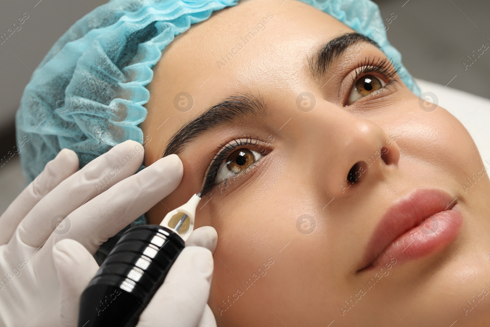 Photo of Young woman undergoing procedure of permanent eyeliner makeup, closeup